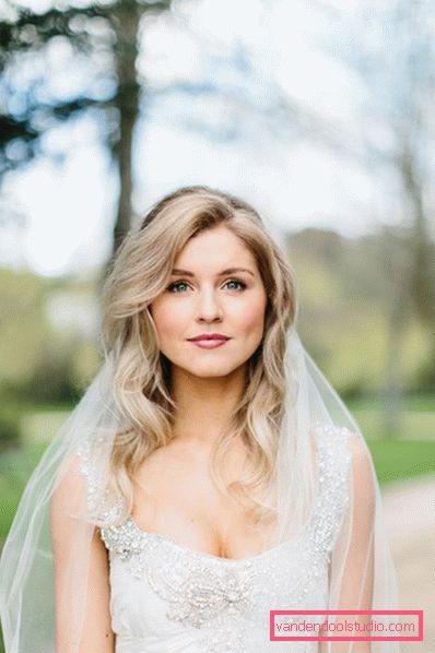 Acconciature da sposa con riccioli fluenti su capelli medi con un velo